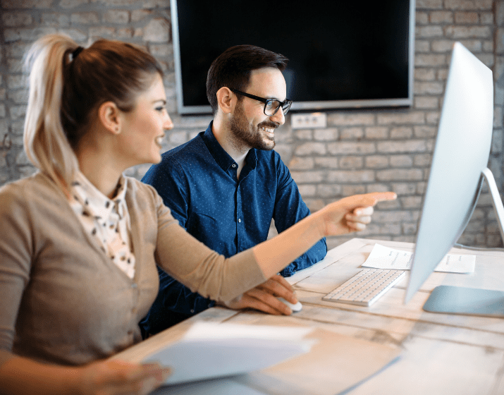 Two IT professionals working on a Mac computer